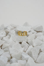 Golden Tranquility Ring for Women rested on top of rocks.