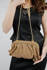 Gold rhinestone clutch bag held at the waist, front view with chain