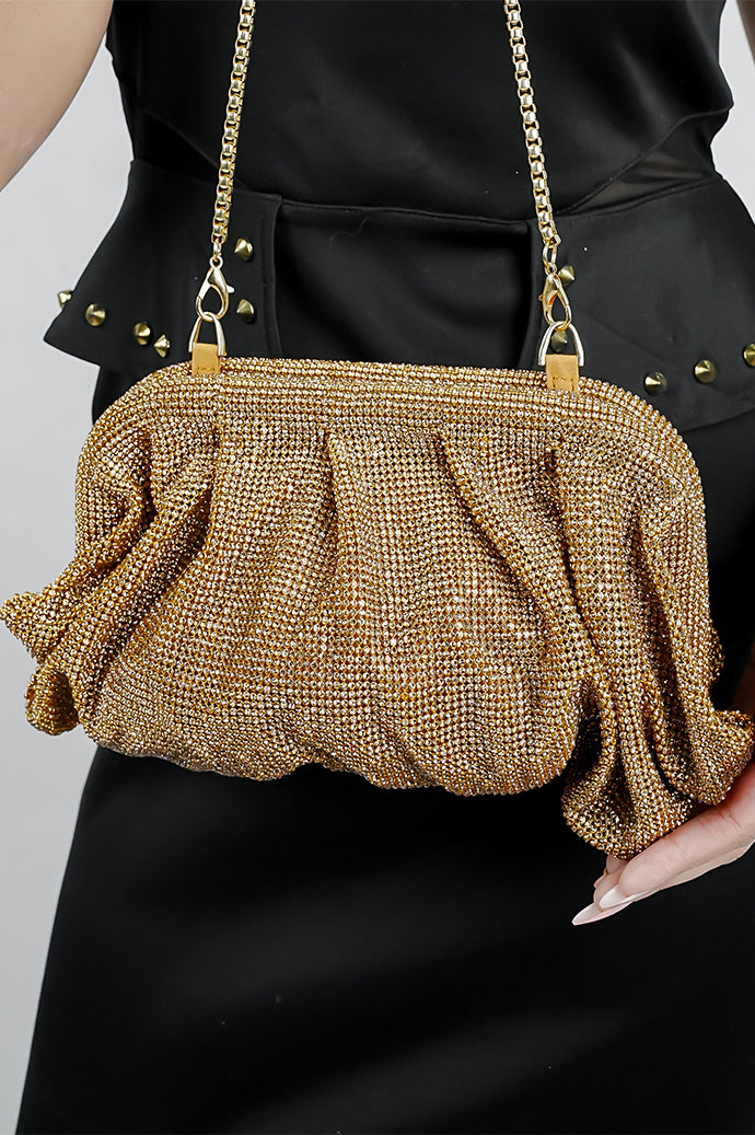 Woman holding a gold Benedetta clutch bag with the chain over her arm