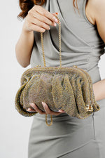 Shimmer Benedetta rhinestone clutch bag held at the waist with a grey dress