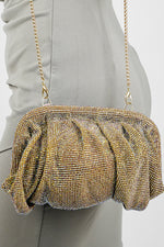 Shimmer clutch bag for women with matching chain, held against a grey dress