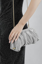 Silver rhinestone mesh clutch bag held in the hand, side view