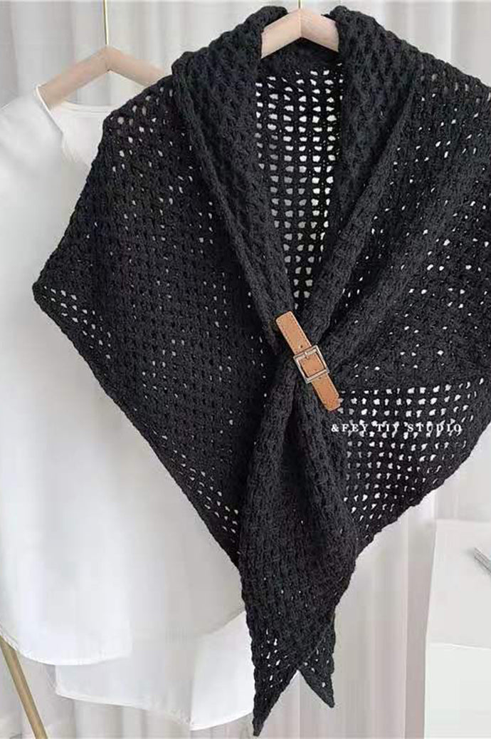 Bohemian open-knit winter cape for women in black with a tan toggle fastener, on a hanger