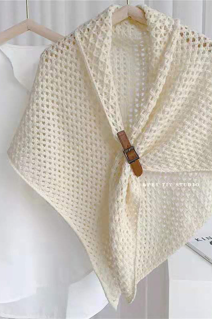 Bohemian open-knit winter cape for women in cream with a tan toggle fastener, on a hanger