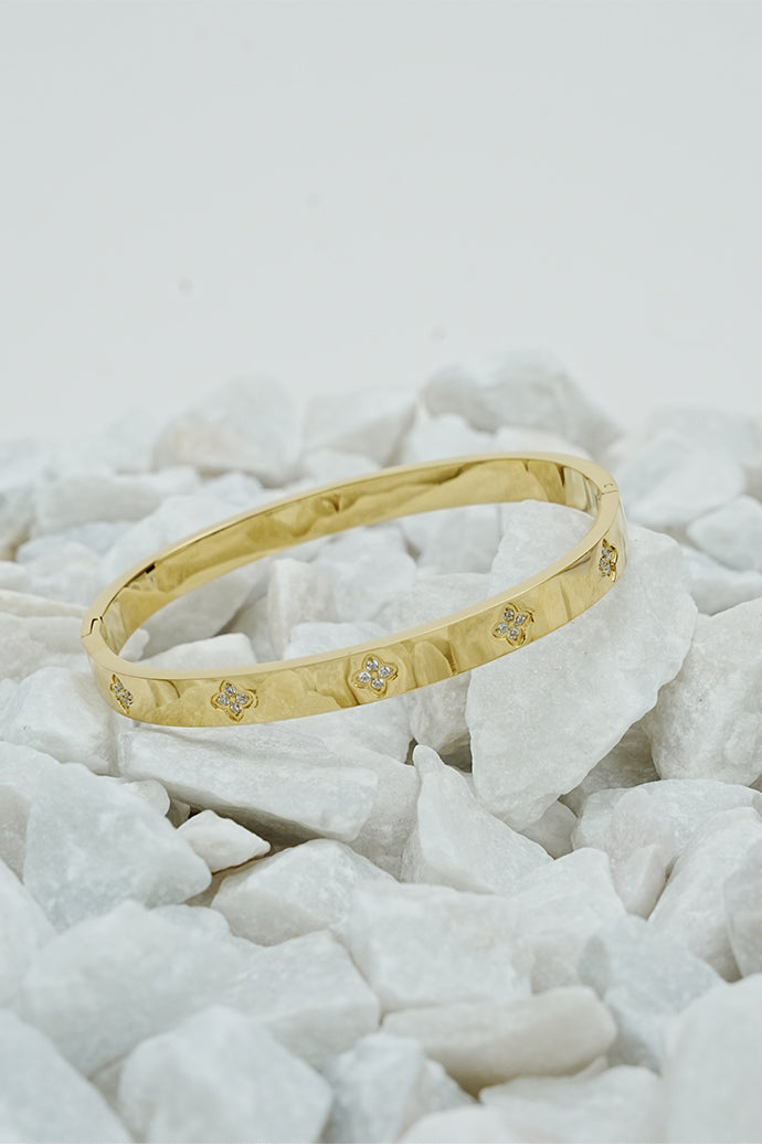 Gold clove stone bangle with small stone accents on white stones
