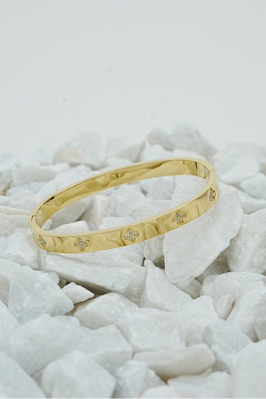 Gold clove stone bangle with small stone accents on white stones