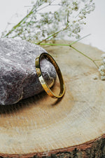 Gold clove stone bangle standing on a wooden slice