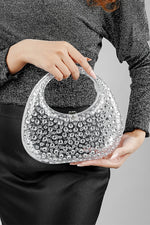 Woman holding a clear clutch bag in both hands at waist level