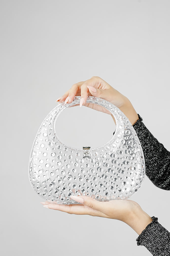 Clear clutch bag for women held by the handle in one hand, side angle