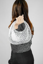 Woman holding a clear clutch bag up behind her shoulder, back view
