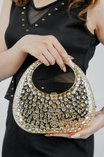 Gold textured clutch bag for women held at waist level with a black top