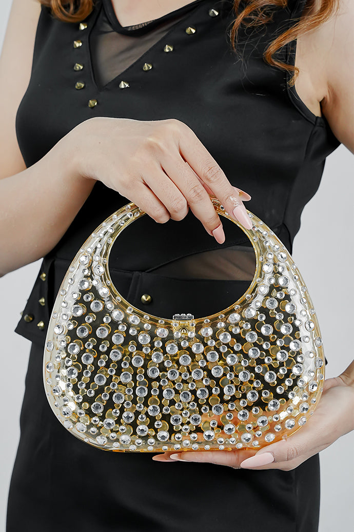 Gold textured clutch bag for women held at waist level with a black top