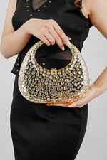 Woman holding a gold clutch bag in both hands, front view