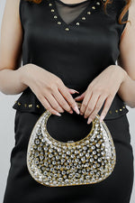 Gold clutch bag for women held by the handle with a black outfit