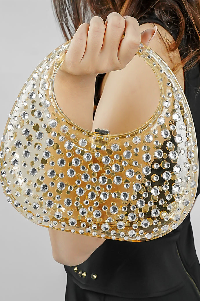 Close-up of a gold textured clutch bag held up by the handle
