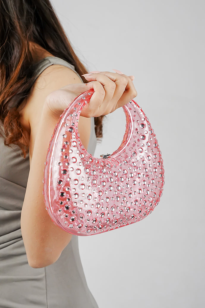 Pink clutch bag for women lifted by the handle, side view