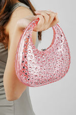 Pink textured clutch bag held up in one hand