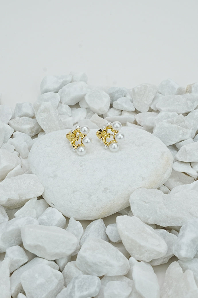 Gold pearl earrings with small pearl beads on a white stone