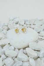 Gold pearl earrings with small pearl beads on a white stone