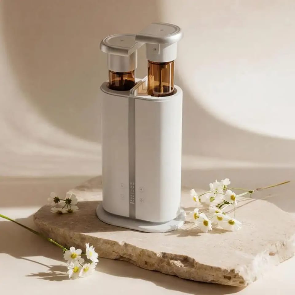Dual scent aroma diffuser with two amber bottles on a stone slab beside white daisies