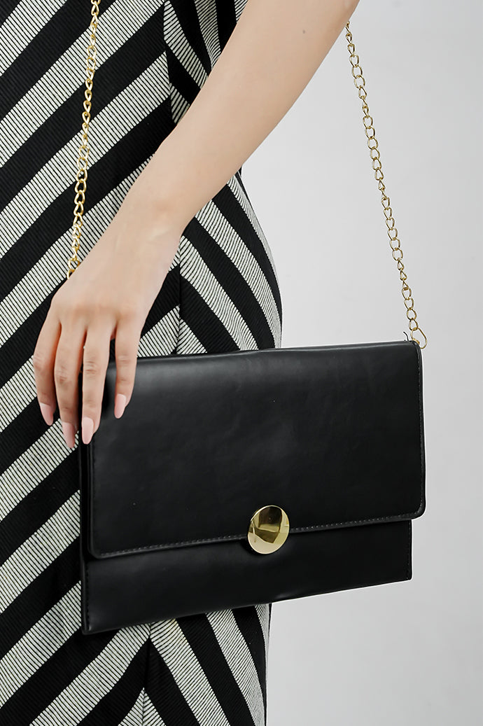 Black Envelope Bag with gold emblem carried on a gold chain strap