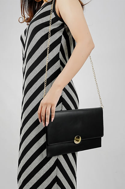 Black Envelope Bag hanging from a gold chain with a striped dress