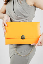 Orange Envelope Bag for women with gold emblem held in front, Future Style Pakistan
