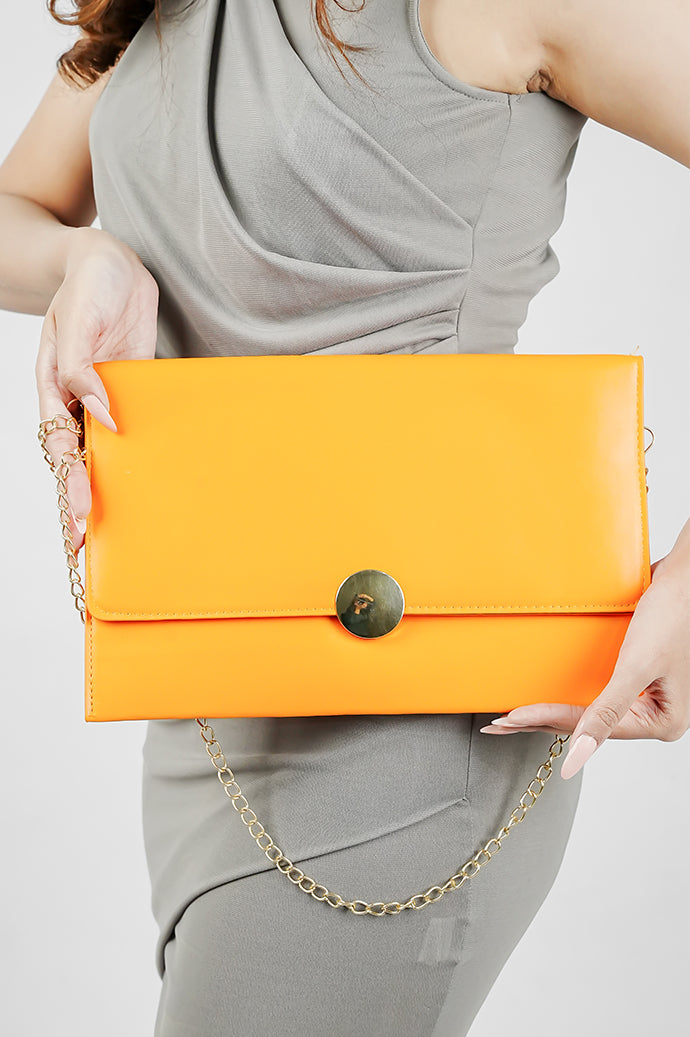 Orange Envelope Bag for women with gold emblem held in front, Future Style Pakistan