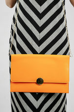 Orange Envelope Bag carried at the waist with a striped dress