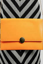 Close-up of the orange Envelope Bag with its gold emblem