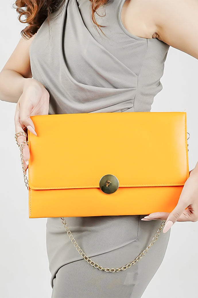 Woman holding the orange Envelope Bag with a gold chain