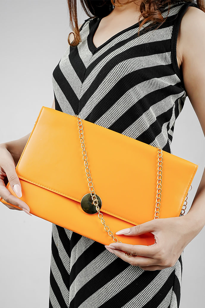 Orange Envelope Bag held in both hands with a striped dress