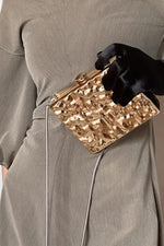 Gold hammered clutch with clasp carried in hand, side view