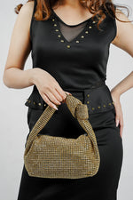 Hubo gold clutch for women held low by its handle with a black top