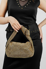Hubo gold sparkling clutch with knotted handle, side view on a model