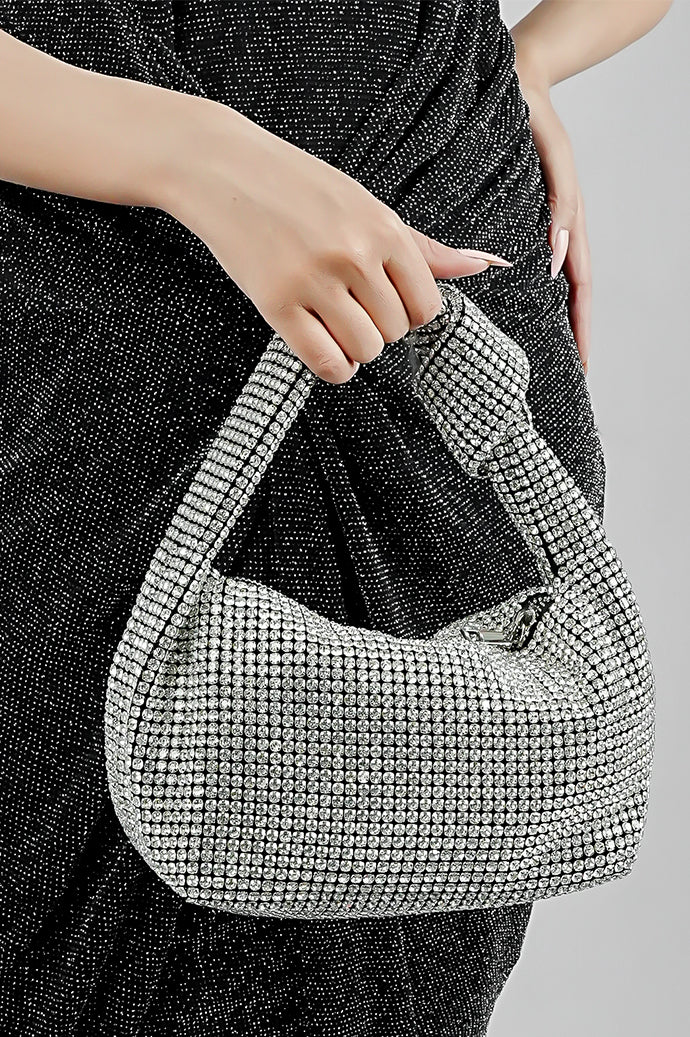 Woman holding the Hubo silver clutch by its handle with a black dress