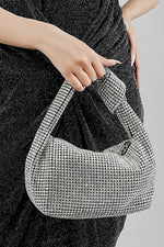 Woman holding the Hubo silver clutch by its handle with a black dress