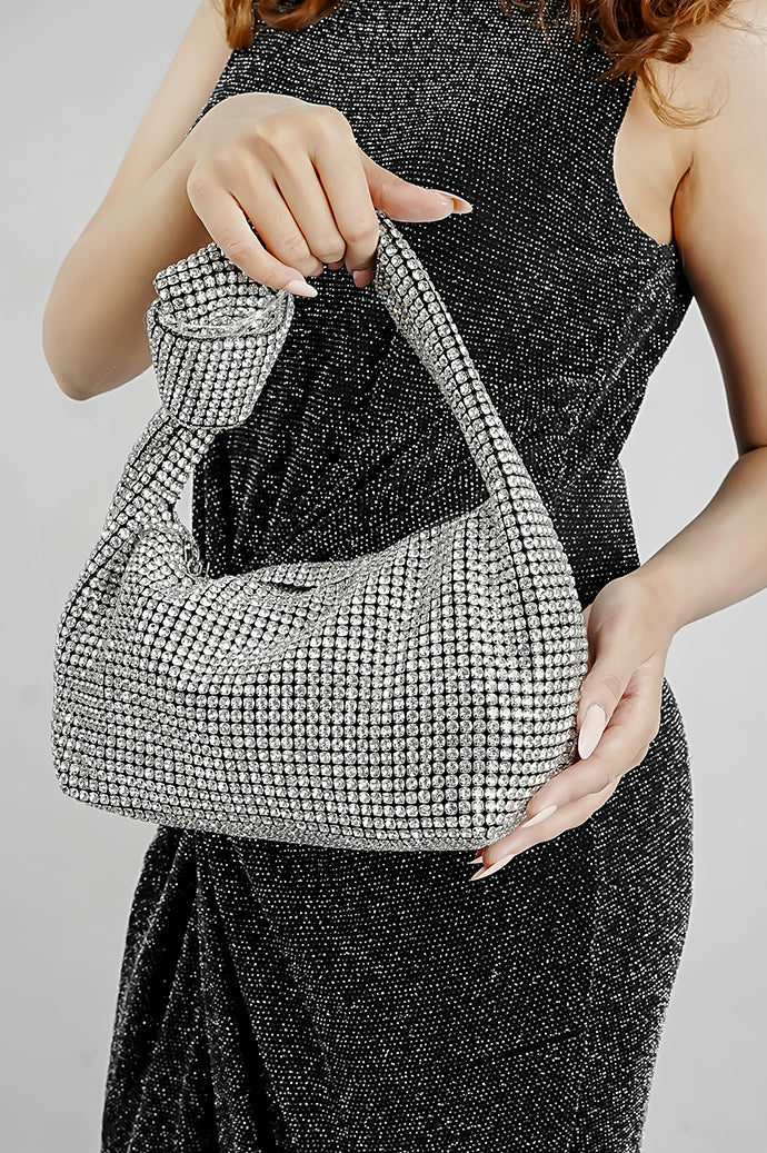 Woman carrying the Hubo silver clutch by its handle, front view