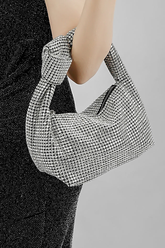 Close-up of the Hubo silver clutch held at the hip by its knot handle