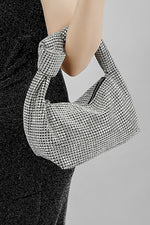 Close-up of the Hubo silver clutch held at the hip by its knot handle