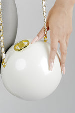 Close-up of the golden clasp on the Luna white globe clutch