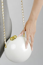Luna white globe clutch with golden clasp and chain, side view