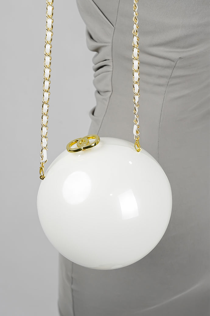 Luna white globe clutch hanging from its gold chain
