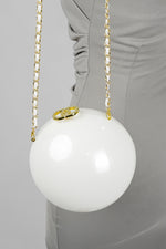 Luna white globe clutch hanging from its gold chain