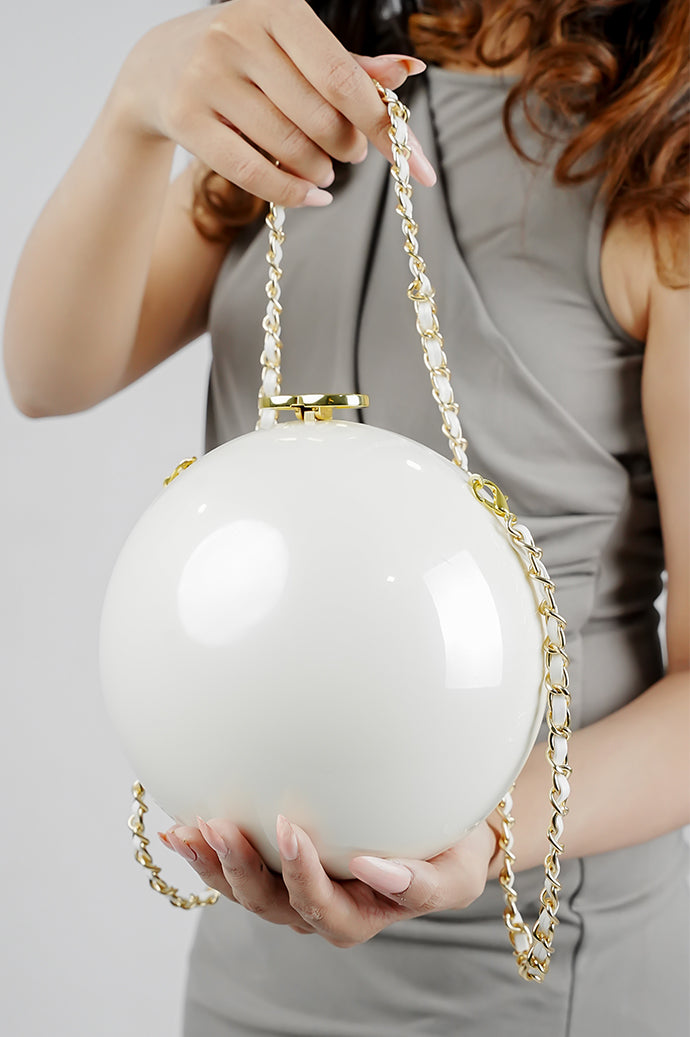 Luna white pearl globe clutch with golden clasp and chain held in both hands, Future Style Pakistan