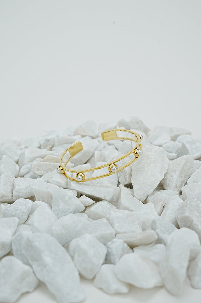 Gold open pearl bangle for women on white stones