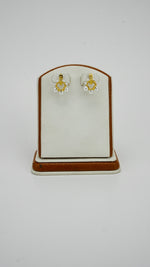 Gold earrings with pearl details for women on a display stand
