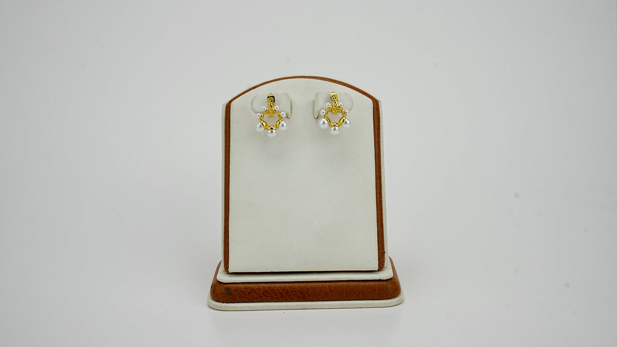 Gold pearl earrings on a display stand