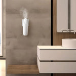 Plug-in aroma diffuser releasing mist on a bathroom wall above a wooden shelf