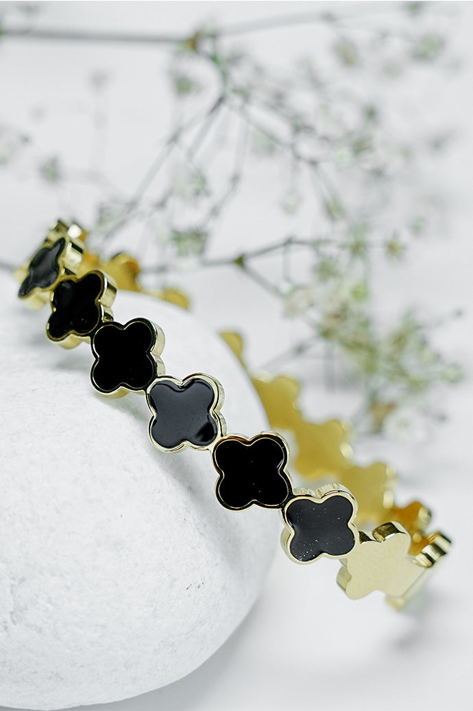 Close-up of black clover pattern on gold Roman style close bangle